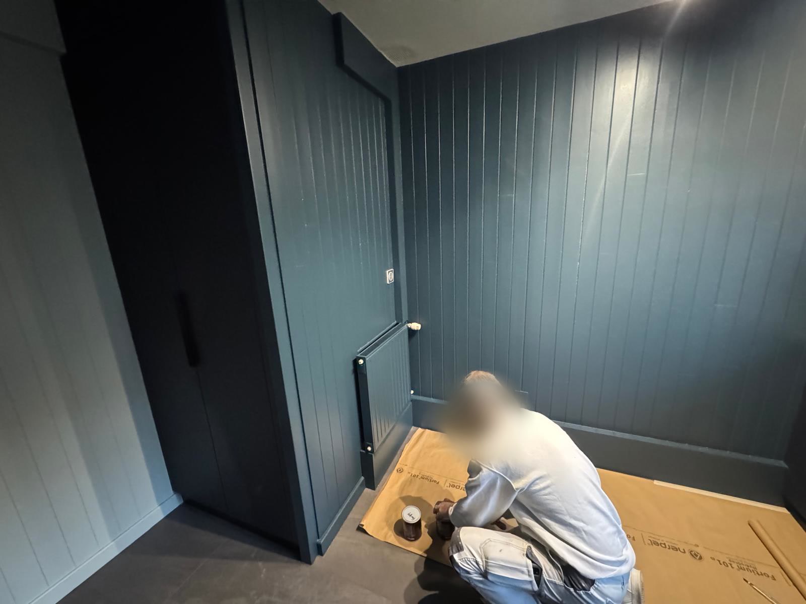Pièce entièrement habillée de lambris peint en bleu nuit, peintre en cours de finition