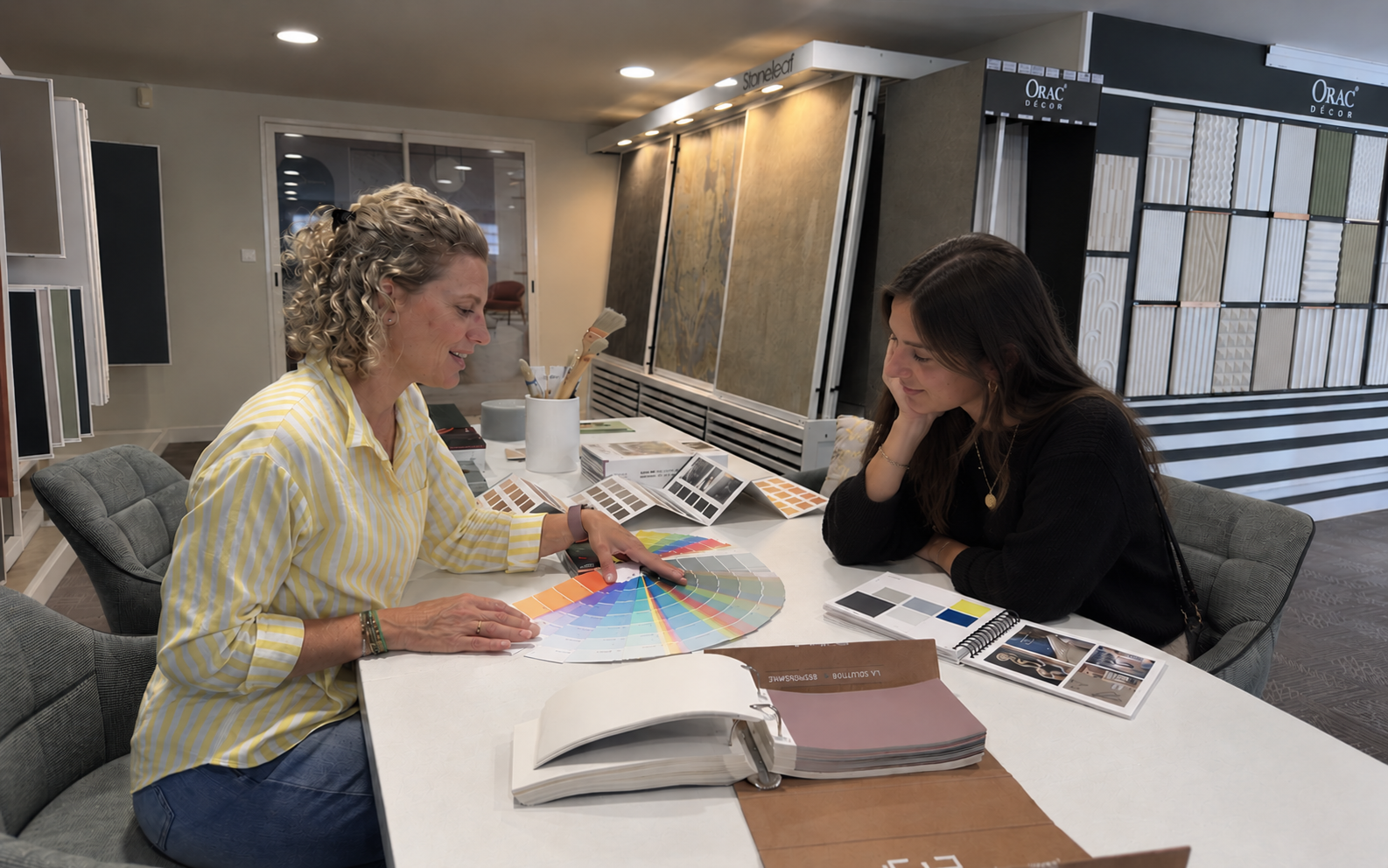 Laure, architecte d’intérieur, présente un nuancier de teintes à une cliente au showroom de Vannes