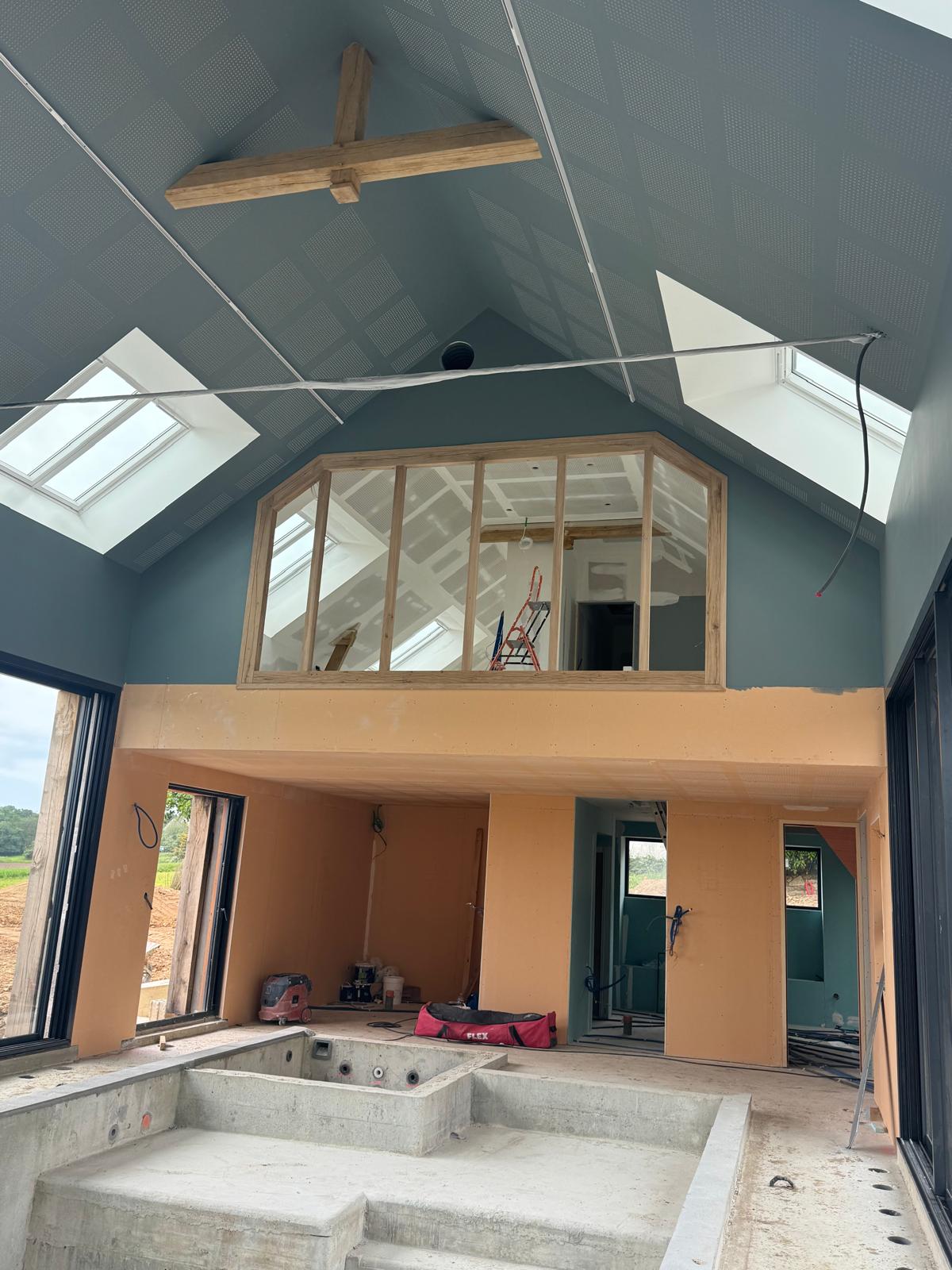 Grande pièce sous charpente aux murs bleu profond, mezzanine et verrière en bois
