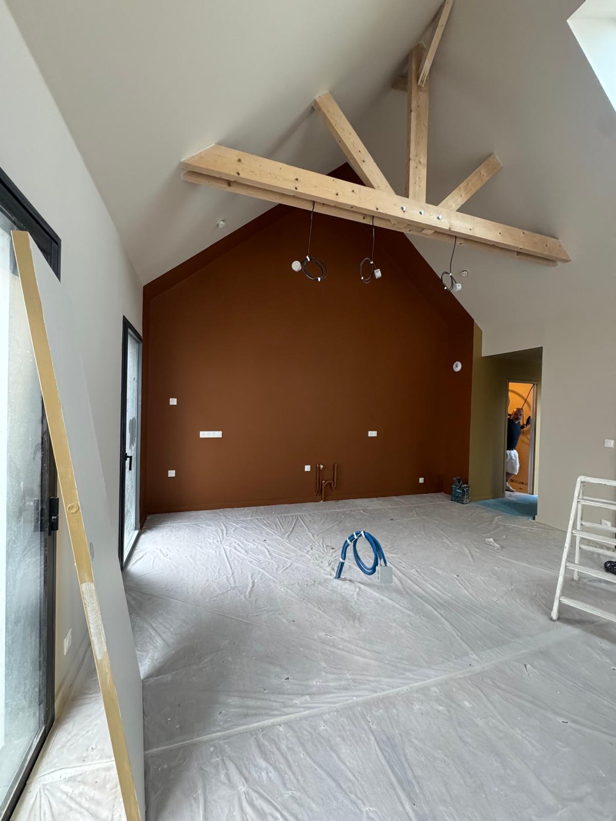 Mur pignon peint en terracotta sous une charpente apparente