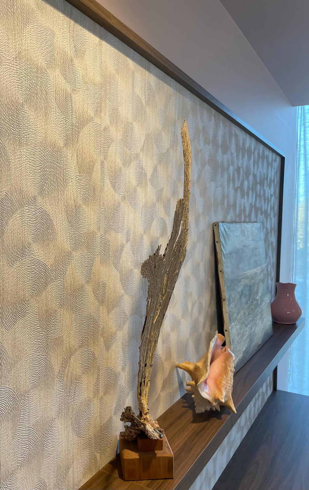 Papier peint à motifs circulaires en relief, encadré de bois au-dessus d’une étagère