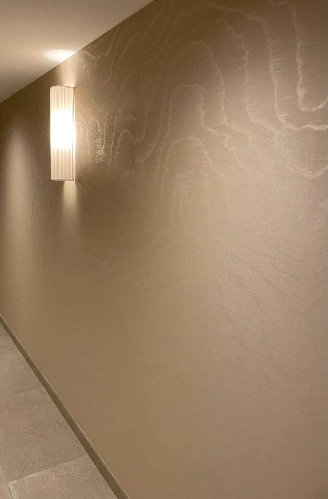 Papier peint aux reflets moirés dans un couloir éclairé par une applique